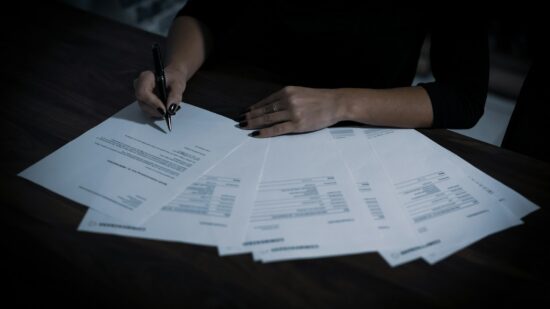A lady signing a contract with a ballpoint pen.